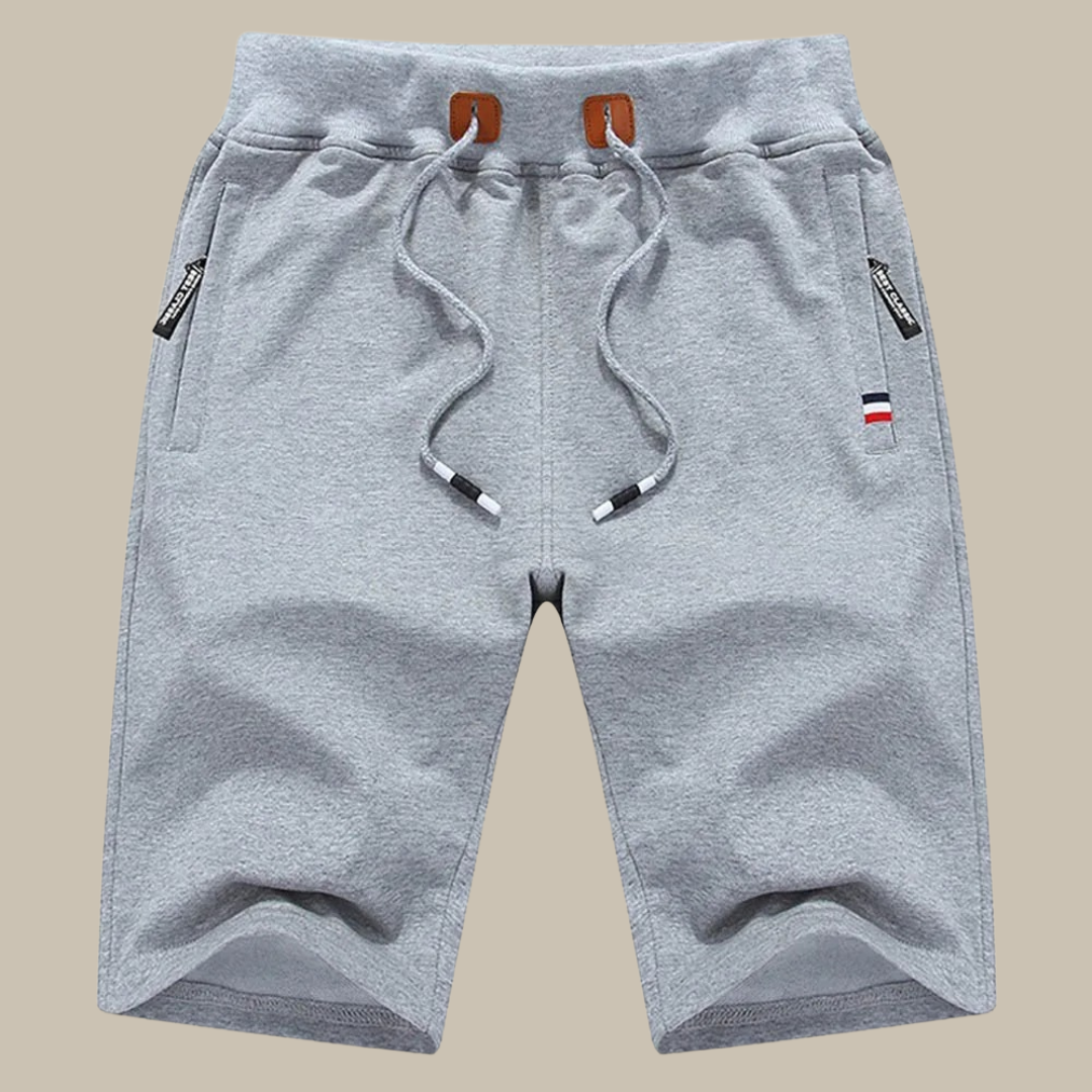 Pantaloncini sportivi grigi da uomo in cotone, con coulisse e tasche laterali con zip. Design casual, ideale per palestra e tempo libero.