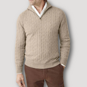 Maglione uomo beige a trecce con zip, collo alto, indossato su camicia bianca e pantaloni marroni. Elegante e casual, moda autunno inverno.