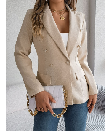 Giacca blazer beige da donna, doppio petto, abbinata a jeans blu e borsa bianca con catena dorata. Look elegante e moderno.