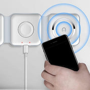 Mano che avvicina smartphone a caricatore wireless magnetico bianco su parete, con cavo USB. Tecnologia di ricarica rapida e innovativa.