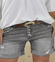 Shorts di jeans grigi da donna con cintura marrone e fibbia dorata, abbinati a maglietta bianca. Stile casual, moda estiva, abbigliamento femminile.