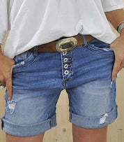 Shorts di jeans blu con bottoni, cintura marrone e dettagli strappati, indossati con maglietta bianca. Moda casual estiva, abbigliamento donna.