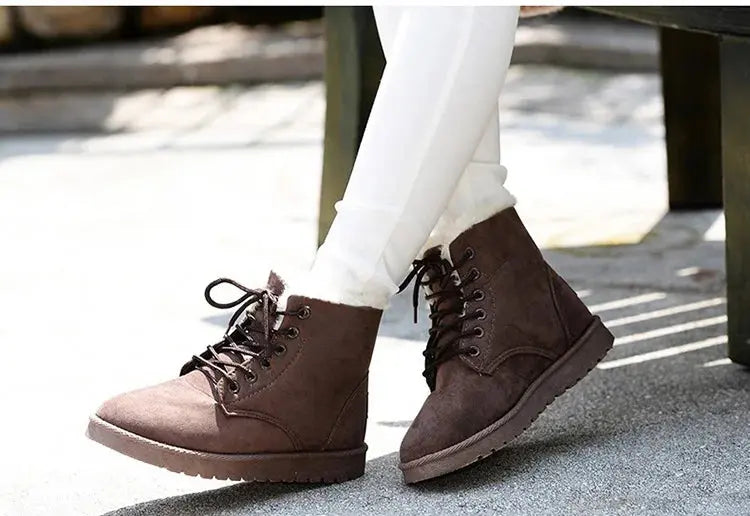 Scarponcini invernali marroni da donna, con lacci, indossati con pantaloni bianchi. Calzature moda casual, comode e calde per la stagione fredda.