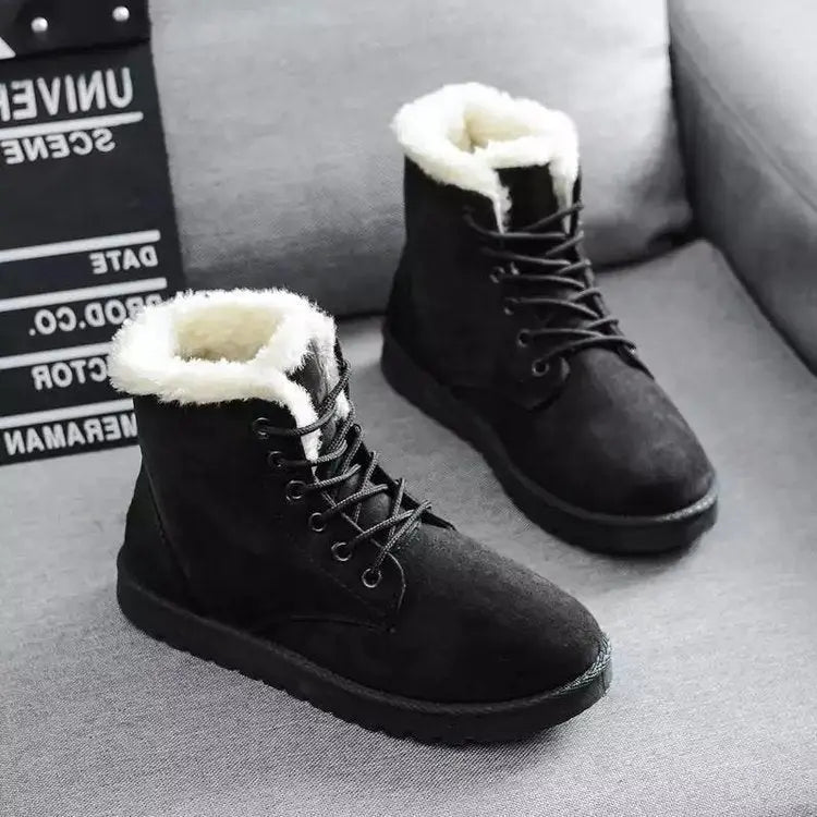 Stivali invernali neri con fodera in pelliccia sintetica bianca, su divano grigio. Scarpe calde e comode, ideali per il freddo.