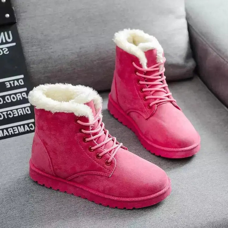 Stivali invernali rosa da donna in pelle scamosciata con fodera in pelliccia sintetica, su divano grigio. Scarpe calde e alla moda per l'inverno.