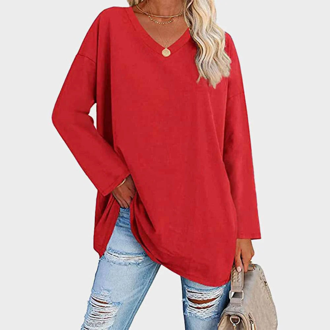 Maglia oversize rossa a maniche lunghe, scollo a V, abbinata a jeans strappati. Look casual e alla moda per donna.