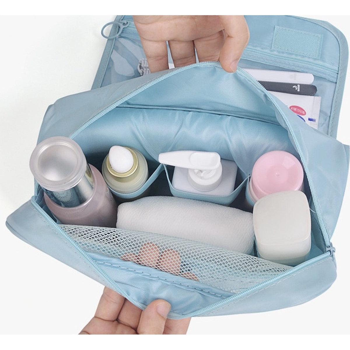 Borsa da toilette azzurra aperta con flaconi cosmetici, dispenser, salviette e tasca a rete. Organizzatore da viaggio per prodotti di bellezza.