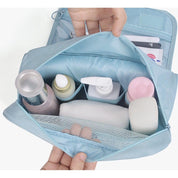 Borsa da toilette azzurra aperta con flaconi cosmetici, dispenser, salviette e tasca a rete. Organizzatore da viaggio per prodotti di bellezza.
