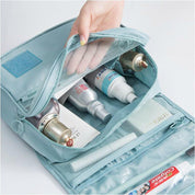 Borsa da viaggio azzurra con scomparti, contenente flaconi di cosmetici, tubetti di crema e spazzolino. Organizzatore da bagno compatto e pratico.