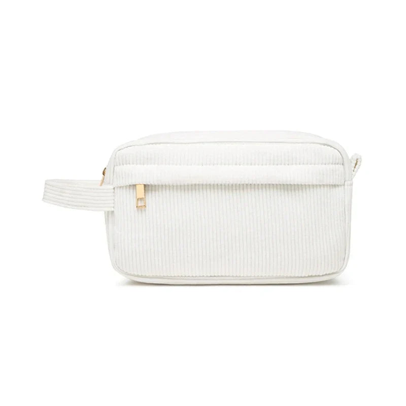 Astuccio da toilette bianco in tessuto a coste, con cerniera dorata e manico laterale. Elegante e pratico per viaggi e organizzazione bagno.