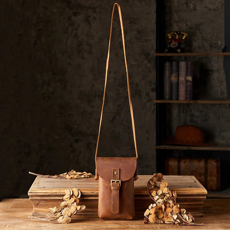 Borsa a tracolla in pelle marrone su tavolo di legno, design vintage, chiusura con fibbia, decorazioni autunnali, sfondo libreria rustica.