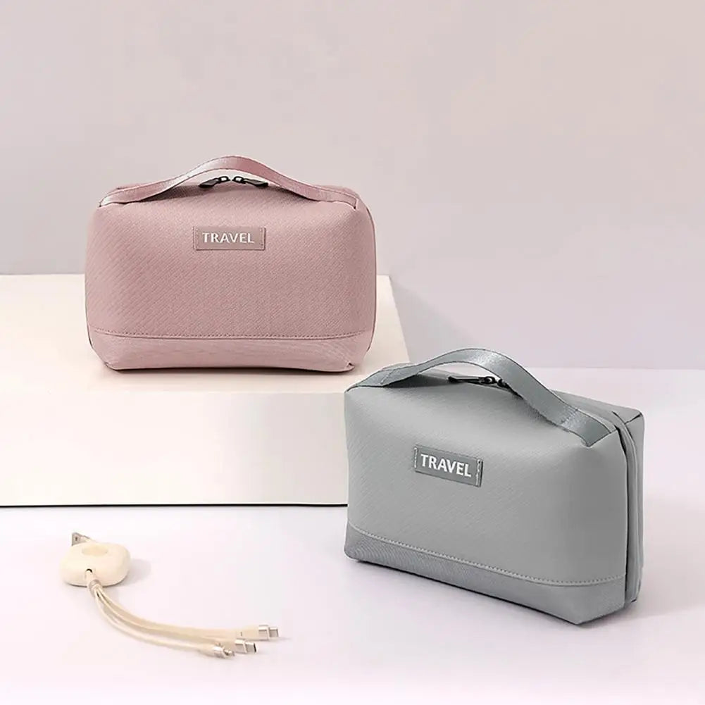 Due beauty case da viaggio in tessuto rosa e grigio con manico, etichetta "TRAVEL", ideali per organizzare cosmetici e accessori.