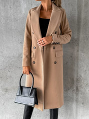 Cappotto lungo beige elegante da donna, doppio petto, abbinato a borsa nera di design, sfondo grigio. Moda autunnale, stile sofisticato.