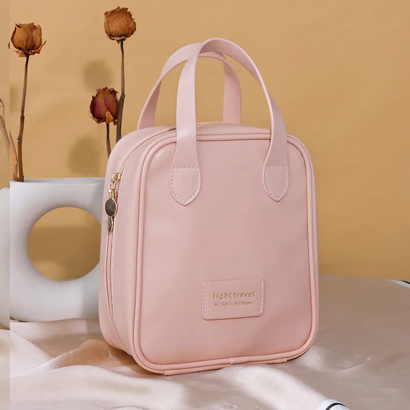 Borsa da viaggio rosa chiaro con manici, design elegante, chiusura a zip dorata, sfondo beige con fiori secchi. Accessorio moda donna.