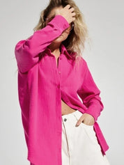 Camicia donna fucsia in cotone, maniche lunghe, abbinata a pantaloni bianchi. Moda casual, stile primaverile, tendenza abbigliamento femminile.
