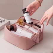 Astuccio da viaggio rosa con scomparti, contenente cosmetici e prodotti per la cura della pelle. Organizzatore trucco elegante e funzionale.
