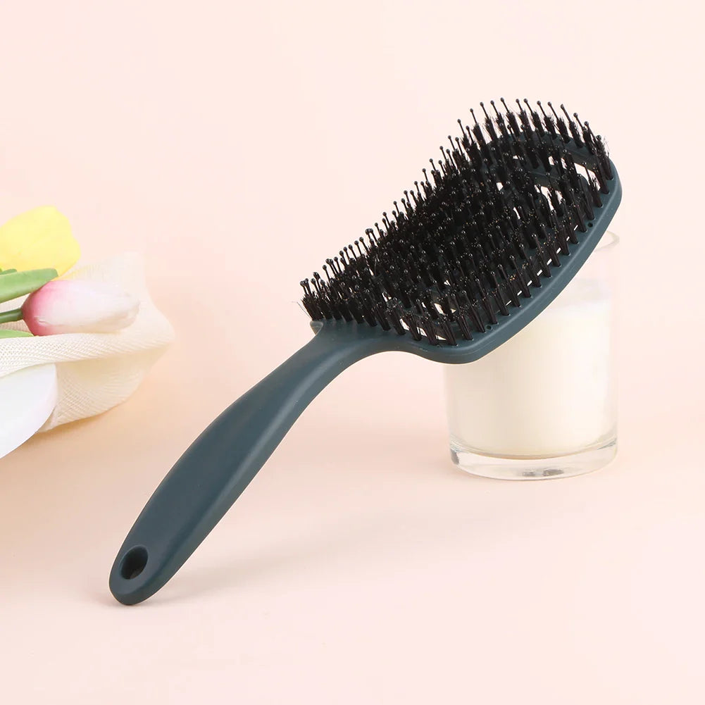 Spazzola per capelli nera con setole morbide su sfondo rosa, ideale per districare e lisciare. Accessorio essenziale per la cura dei capelli.