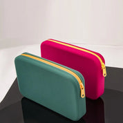 Due astucci rettangolari in silicone, uno verde e uno rosa, con cerniera gialla, su sfondo bianco. Accessori moda, organizzazione, praticità.