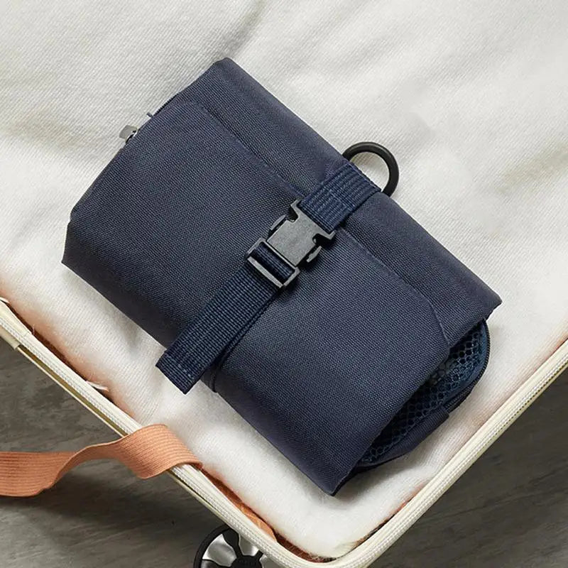 Custodia da viaggio blu scuro con fibbia, compatta e pieghevole, ideale per organizzare accessori in valigia. Accessorio da viaggio essenziale.