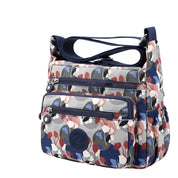 Borsa a tracolla Kipling multicolore con stampa floreale, tasche multiple e chiusura zip. Design moderno e funzionale per uso quotidiano.