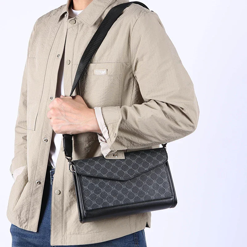 Borsa a tracolla uomo in pelle nera con motivo geometrico, indossata su giacca beige. Accessorio moda elegante e versatile.
