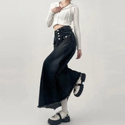 Gonna lunga nera in denim con bottoni, abbinata a top bianco a coste e stivali chunky bianchi. Moda casual donna, stile urbano.