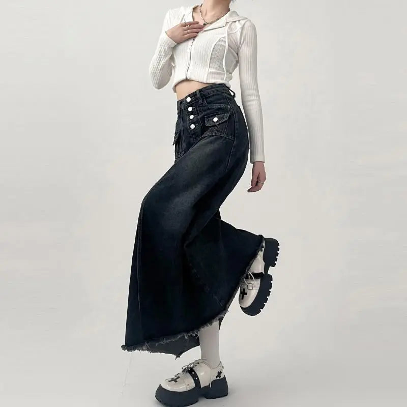 Gonna lunga nera in denim con bottoni, abbinata a top bianco a coste e stivali chunky bianchi. Moda casual donna, stile urbano.