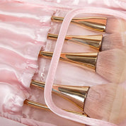 Set di pennelli trucco con manici dorati e setole morbide, custoditi in una custodia rosa satinata. Accessori cosmetici eleganti e di alta qualità.