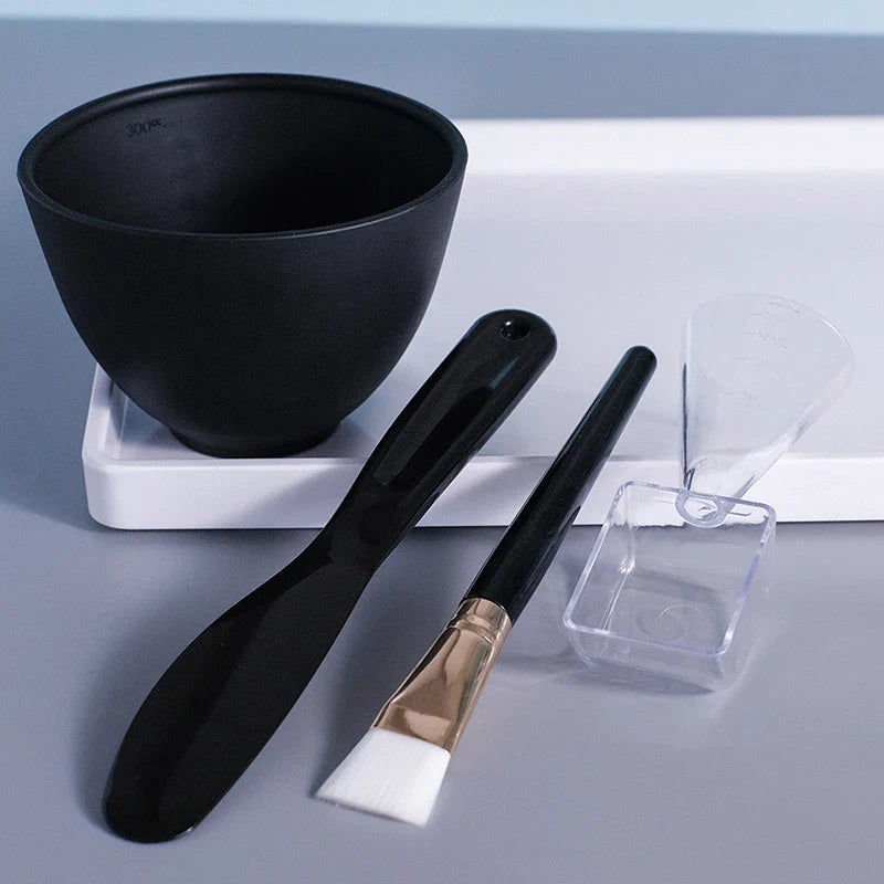 Set di strumenti per maschera viso: ciotola nera, spatola, pennello, misurino e cucchiaio trasparente. Ideale per miscelare e applicare maschere facciali.