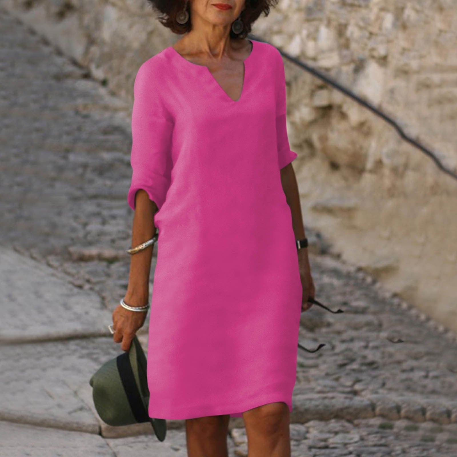 Abito rosa donna, maniche a tre quarti, scollo a V, stile casual, strada acciottolata, moda estiva, accessori bracciali, cappello verde.