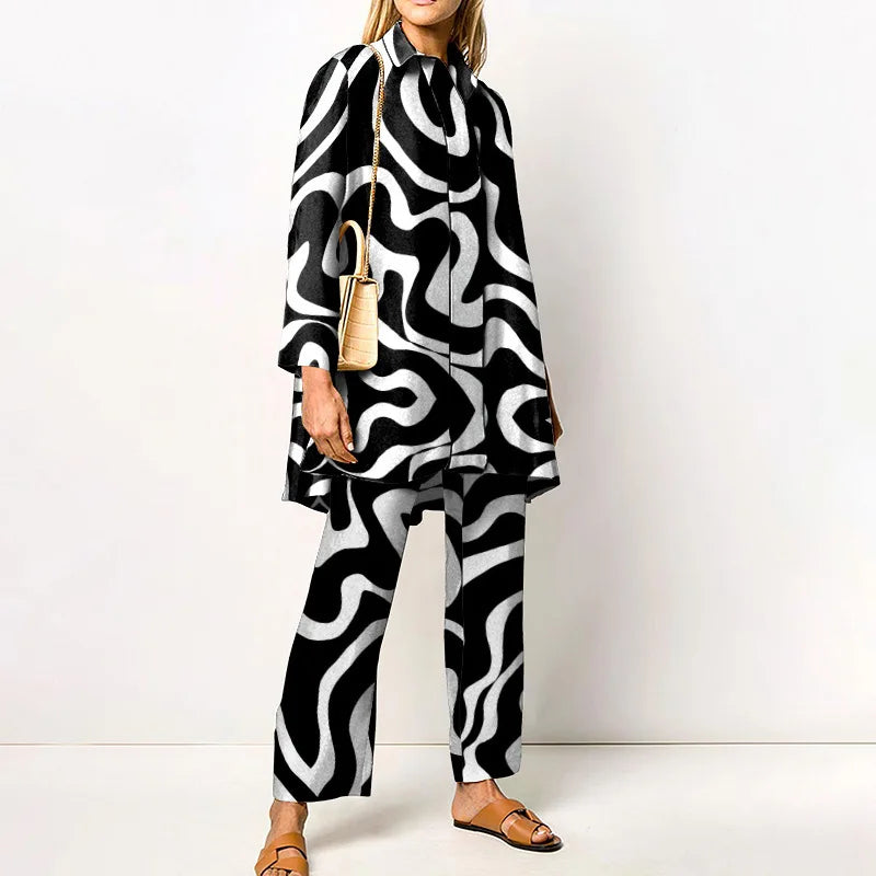 Abito donna elegante con motivo astratto bianco e nero, borsa a tracolla beige, sandali marroni. Moda contemporanea, outfit chic.