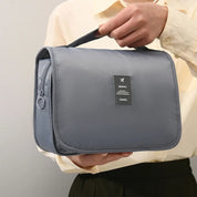 Borsa da viaggio grigia impermeabile con manico, ideale per organizzare articoli da toeletta. Design compatto, perfetto per viaggi e spostamenti.