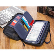 Portafoglio da viaggio nero aperto con scomparti per carte di credito, banconote e documenti, su tavolo di legno, ideale per organizzazione e sicurezza.
