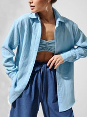 Modella indossa camicia azzurra in cotone, abbinata a top e pantaloni blu. Moda donna casual, abbigliamento estivo leggero e traspirante.