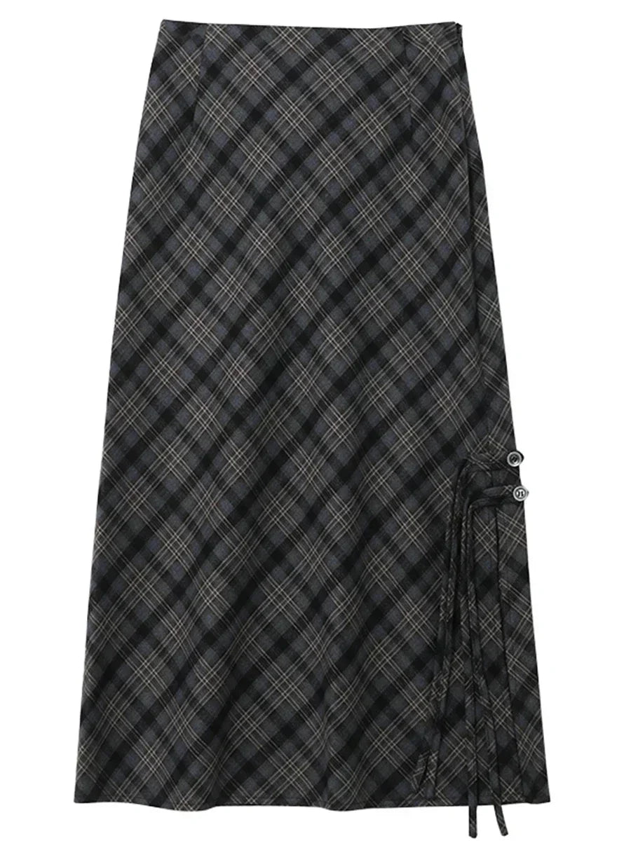 Gonna lunga a quadri neri e grigi, stile scozzese, con dettagli a laccio laterali. Elegante e versatile, perfetta per moda autunno-inverno.