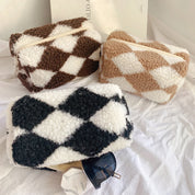 Tre astucci in tessuto peluche a rombi marroni, beige e neri su sfondo bianco, con occhiali da sole. Accessori moda, design elegante e moderno.