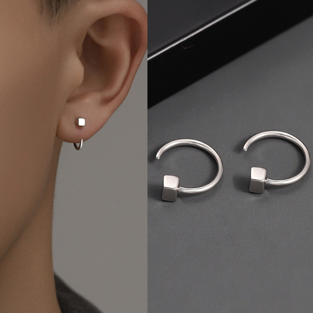 Orecchini a cerchio in argento con ciondolo cubico, design minimalista, indossati su lobo. Gioielli moderni, eleganti, adatti per ogni occasione.