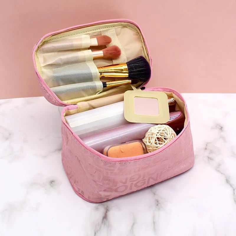 Astuccio trucco rosa aperto su sfondo marmo, con pennelli, cipria, rossetto e accessori. Organizzatore cosmetici da viaggio elegante e pratico.