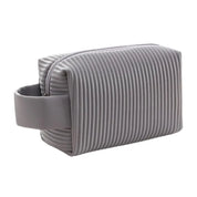 Astuccio da viaggio grigio con design a coste, manico laterale e chiusura a zip. Ideale per cosmetici e accessori. Elegante e funzionale.