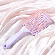 Spazzola per capelli quadrata in plastica viola con setole rosa su tessuto bianco. Accessorio per styling, cura dei capelli, bellezza quotidiana.