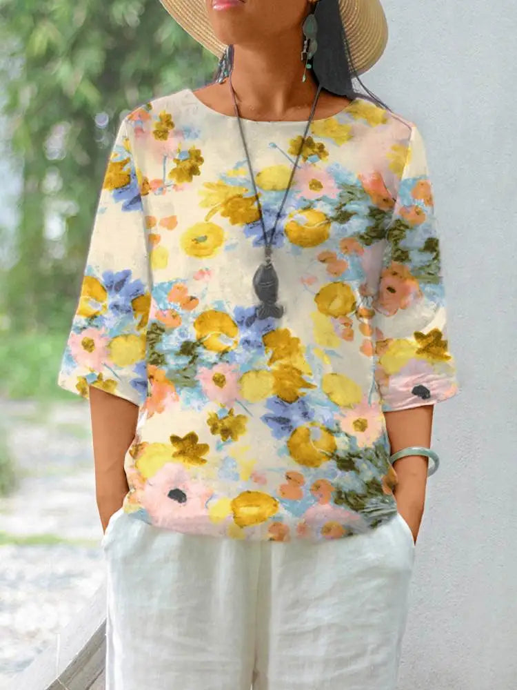 Maglietta donna floreale, maniche corte, colori pastello, cotone leggero, stile casual estivo, abbinata a pantaloni bianchi, accessori boho.