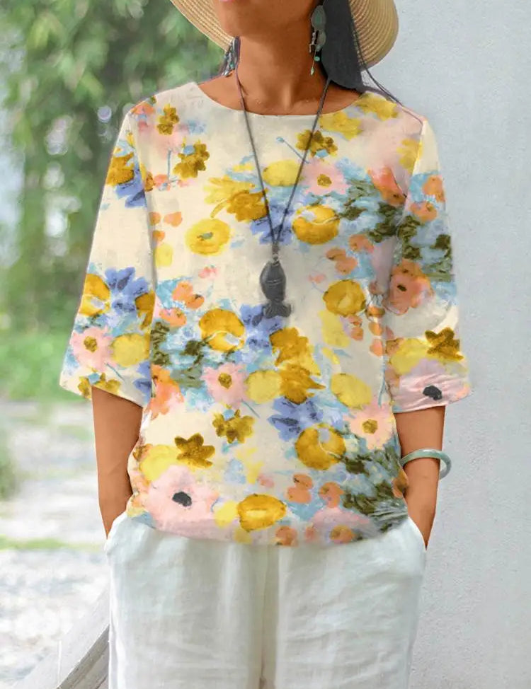 Maglietta donna floreale, maniche corte, colori pastello, cotone leggero, stile casual estivo, abbinata a pantaloni bianchi, accessori boho.