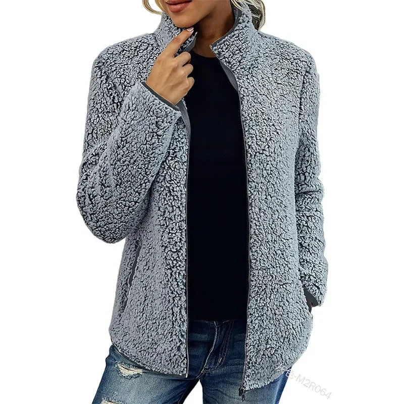 Giacca in pile grigio donna, stile casual, con zip frontale, collo alto, abbinata a jeans strappati. Ideale per look autunnali e invernali.