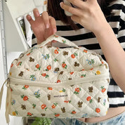 Borsa trapuntata bianca con stampa floreale e orsacchiotti, manico superiore, chiusura a zip, tenuta da una persona. Accessorio moda casual.