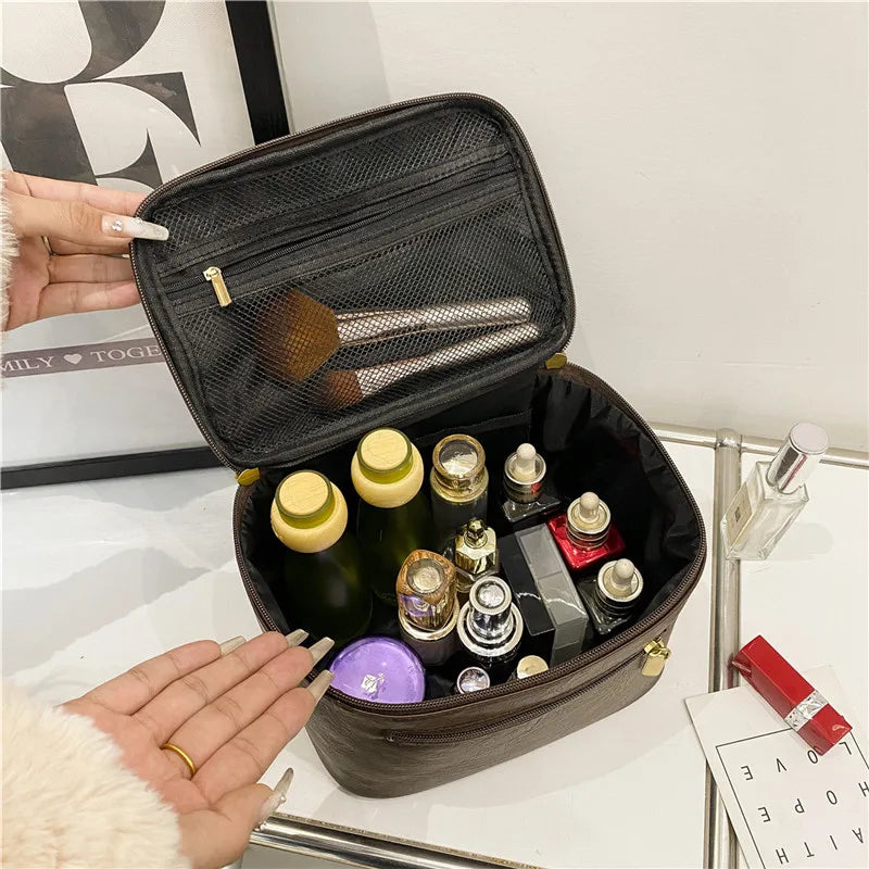 Borsa cosmetica aperta con flaconi di profumo, pennelli trucco e prodotti skincare. Organizer da viaggio elegante e capiente per cosmetici.