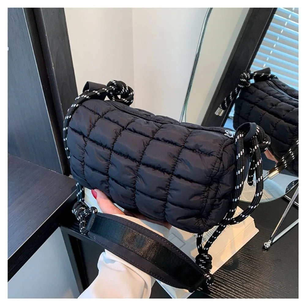 Borsa a tracolla nera trapuntata con manici a corda, design moderno, riflessa in uno specchio. Accessorio moda donna, elegante e versatile.