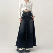 Donna con gonna lunga in denim nero a vita alta, abbinata a top bianco a coste. Moda casual, abbigliamento femminile trendy, stile urbano.