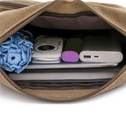 Interno di una borsa marrone con fotocamera, power bank, ombrello blu e tablet. Accessori tecnologici e da viaggio organizzati.