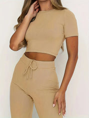 Donna in abbigliamento coordinato beige a coste, top corto e pantaloni a vita alta. Moda femminile, stile casual, tendenza 2023.