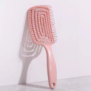 Spazzola districante rosa con setole flessibili, design ergonomico, ideale per capelli ricci e lisci. Accessorio per cura dei capelli.